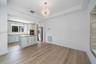 Tray ceiling with recessed lighting, central crystal-style chandelier, wood-finish flooring, kitchen island with stone countertop, and stainless steel