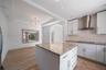 Kitchen featuring white cabinetry, stone-surfaced center island, stainless steel chimney-style range hood, recessed lighting, and wood-finish flooring