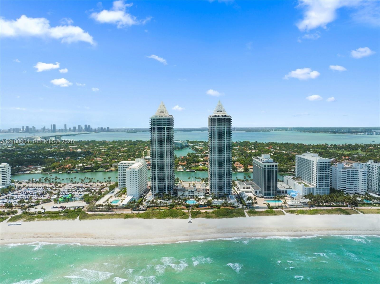 Aerial view featuring twin high-rise towers situated on a coastal beachfront with direct ocean access and proximity to local waterways