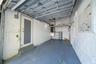 Enclosed garage featuring painted concrete block walls, painted concrete flooring, exposed ceiling joists, a dedicated utility area with a water heate