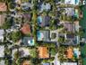 Aerial perspective of a coastal residential neighborhood featuring waterfront properties, private swimming pools, paved driveways, and mature landscap