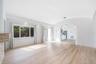 Living area featuring wood-finish flooring, a vaulted barrel-style ceiling, arched wall openings, a stacked-stone fireplace surround, and sliding glas