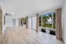 Sun-filled room featuring wood-finish flooring, a vaulted ceiling, floor-to-ceiling windows, and dual glass entry doors