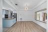 Wood-finish flooring, tray ceiling with recessed lighting, central crystal-style chandelier, and stone-accented interior wall opening