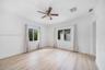 Bright room featuring wood-finish flooring, dual windows with sliding panes, and a ceiling-mounted fan with integrated lighting