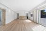 Vaulted ceiling featuring recessed lighting, stacked stone accent wall, integrated beverage refrigerator, and wood-finish flooring with sliding glass 