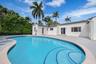 Curved swimming pool featuring built-in steps and a surrounding paved patio
