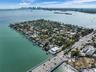 Aerial view of coastal peninsula featuring expansive waterfront access, mature tropical landscaping, and integrated private boat docking facilities