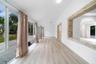 Light-filled interior featuring expansive floor-to-ceiling glass sliding doors, wood-finish flooring, a vaulted ceiling, and stacked-stone decorative 