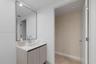 Bathroom vanity featuring light-toned cabinetry, a solid surface countertop with an integrated rectangular sink, a polished chrome bridge faucet, and 
