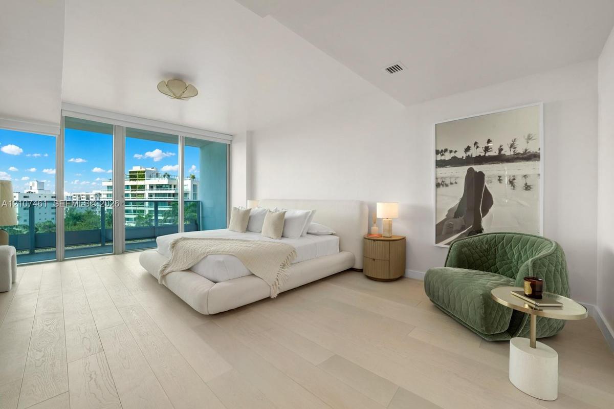 Floor-to-ceiling glass sliding doors, wood-finish flooring, and expansive balcony access featuring a metal railing