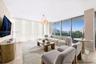 Living area featuring floor-to-ceiling glass windows, wood-finish flooring, and a contemporary multi-bulb pendant light fixture