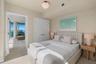 Light-toned wood-finish flooring, white double-door closet with modern hardware, and decorative petal-shaped ceiling light fixture