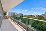 Covered balcony featuring a sleek glass railing with metal framing and concrete flooring