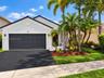Stucco exterior with a tiled roof, asphalt driveway, two-car garage, and established palm landscaping