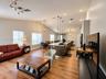 Open-concept space featuring wood-finish flooring, vaulted ceilings, a kitchen island with stone-finish countertops, apron-front sink, and pendant lig