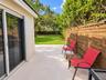 Backyard featuring large-format light-toned patio tiles, horizontal wood privacy fencing, and a manicured lawn