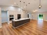 Open-concept kitchen featuring vaulted ceilings, wood-finish flooring, a central island with a solid surface countertop, light-toned cabinetry, and bu