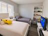 Room featuring wood-finish flooring, neutral wall paint, and multi-pane window with adjustable blinds