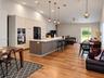 Open-concept kitchen featuring full-height light wood-finish cabinetry, a large center island with contrasting wood-finish paneling and quartz counter
