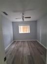 Room featuring wood-finish flooring, a neutral paint palette, and a ceiling-mounted fan with integrated lighting