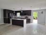Kitchen featuring dark cabinetry, a waterfall-edge stone island, stainless steel appliances, and wood-finish flooring