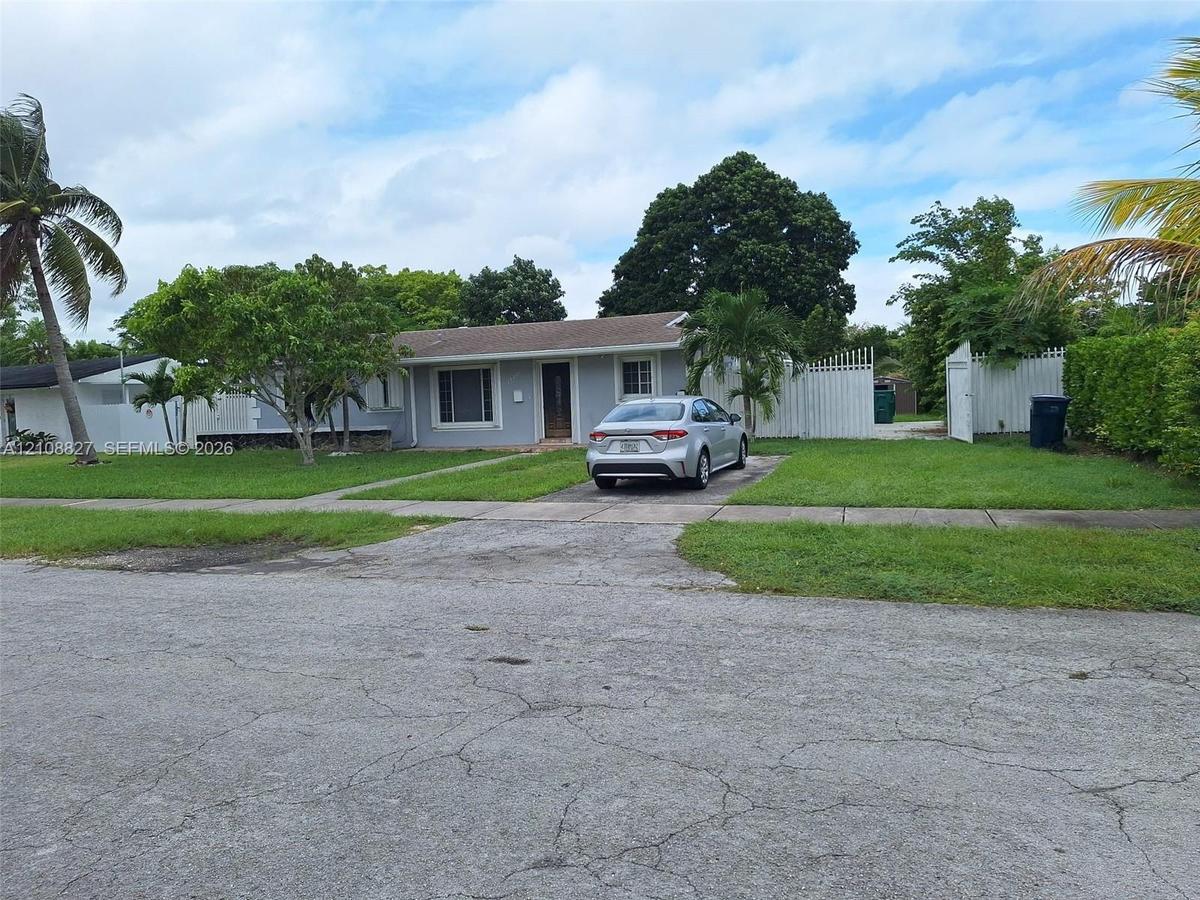 Single-story residence with a concrete driveway, multi-pane windows, and a privacy fence
