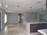 Kitchen featuring a central island with a stone-composite countertop, dark wood-finish cabinetry, neutral wall paint, wood-finish flooring, and pendan