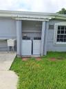 Exterior laundry alcove featuring folding privacy doors, built-in shelving, and a utility sink