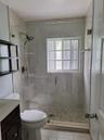 Walk-in shower featuring a frameless glass enclosure, pebble tile flooring, oversized wall tile, and a multi-function showerhead, complemented by a da