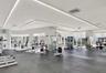 Fitness center featuring resilient rubber flooring, recessed architectural LED lighting, expansive floor-to-ceiling windows, and mirrored wall surface