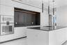 Contemporary kitchen featuring floor-to-ceiling flat-panel cabinetry, a central island with a solid-surface countertop, integrated wall-mounted ovens,