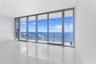 Floor-to-ceiling glass panel windows, sliding glass door, polished tile flooring, and private balcony with metal and glass railing