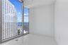 Floor-to-ceiling windows featuring expansive urban and water scenery, complemented by crisp white walls and light-toned tile flooring