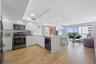 Modern kitchen featuring white flat-panel cabinetry, wood-finish flooring, quartz countertops, stainless steel appliances, and glass sliding doors