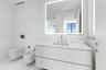 Modern floating vanity with a seamless countertop, wall-mounted commode and bidet, large-format tile wall cladding, and an integrated LED backlit mirr