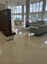 Grand lobby featuring floor-to-ceiling windows, polished stone flooring, custom decorative wood partition, and spherical pendant lighting