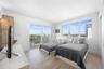 Wood-finish flooring, sliding glass door with balcony access, and large windows with exterior urban scenery