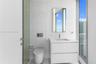 Modern wall-mounted floating vanity with integrated rectangular sink and stone countertop, illuminated rectangular mirror, floor-to-ceiling windows, a