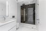 Modern bathroom featuring a floating white vanity with a rectangular sink, wall-mounted faucet, walk-in shower with floor-to-ceiling glass enclosure, 