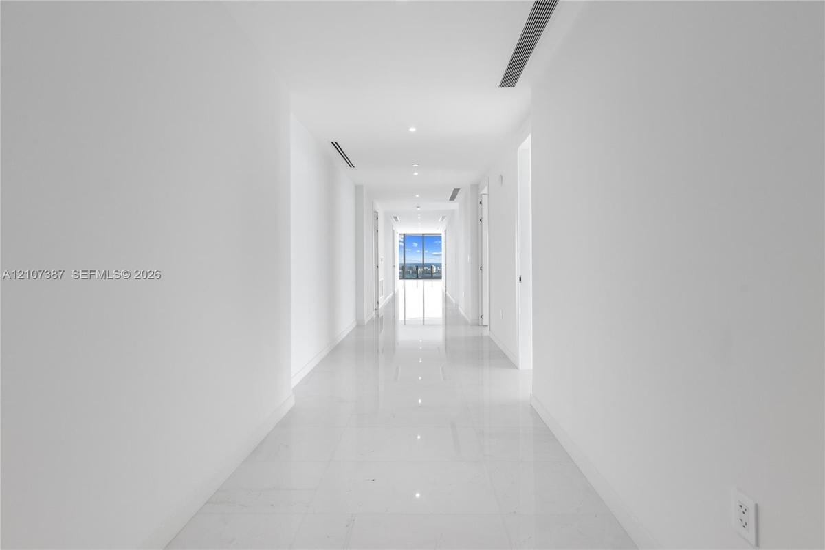Hallway featuring polished tile flooring, recessed ceiling lighting, and floor-to-ceiling windows