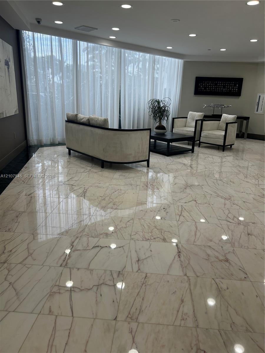 Polished stone flooring with veining detail, floor-to-ceiling sheer window treatments, and recessed ceiling lighting