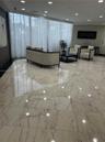 Polished stone flooring with veining detail, floor-to-ceiling sheer window treatments, and recessed ceiling lighting