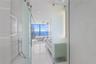Floor-to-ceiling glass paneling, floating double vanity, freestanding soaking tub, large-format tile flooring, and integrated ceiling rain showerhead