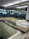 Fitness area featuring full-wall mirrors, recessed lighting, and a built-in service counter with a dark wood-finish top