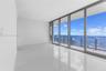 Floor-to-ceiling glass wall, polished tile flooring, recessed ceiling lighting, and expansive balcony with glass panel railing