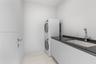 Laundry room featuring stacked washer and dryer, flat-panel cabinetry, dark stone-finish countertop, undermount sink, and high-arc chrome faucet