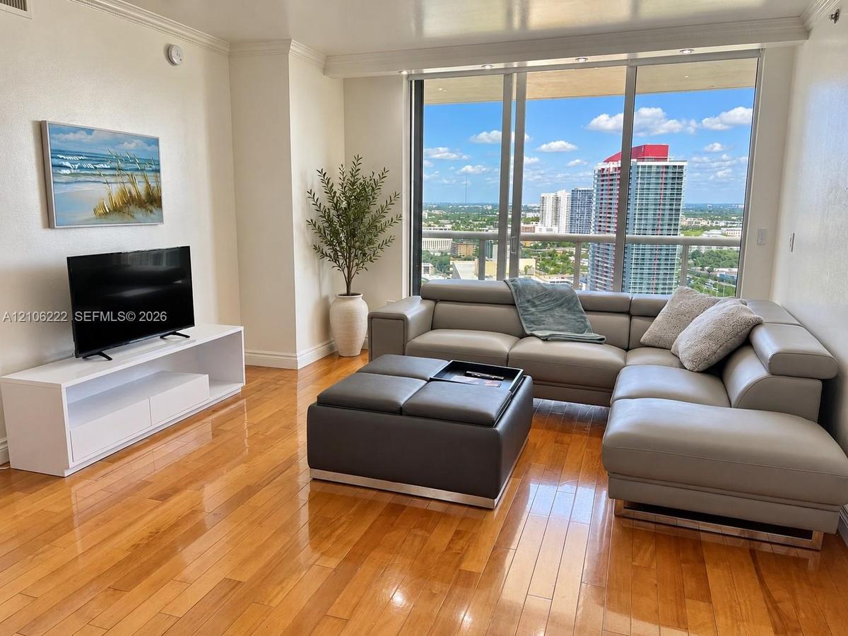 Living space featuring polished wood-finish flooring, floor-to-ceiling windows, and a private balcony