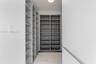Custom walk-in storage featuring grey floor-to-ceiling shelving, light-toned tile flooring, and integrated overhead lighting