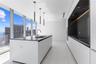 Kitchen featuring white flat-panel cabinetry, a central island with a contrasting stone-finish countertop, stainless steel undermount sink, floor-to-c
